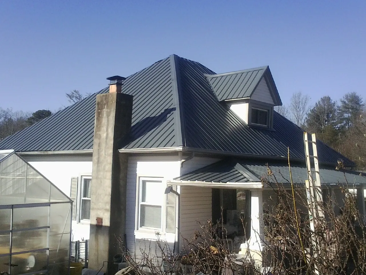 Dark blue standing seam metal roof on a white farmhouse with dormer — Slate & Tile Roof Repair by Roofing Brothers in Coraopolis