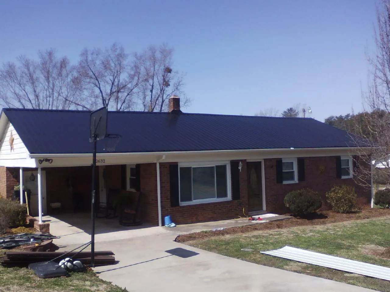 Finished dark blue metal roof on a brick ranch with a carport in Coraopolis
