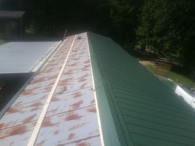 Old rusted panels beside newly installed green metal roofing — Wind Damage Roof Repair by Roofing Brothers in Coraopolis