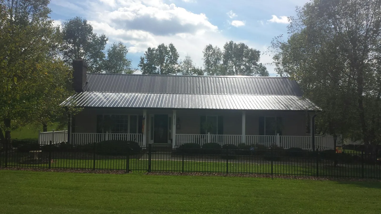 Gray metal roof on a brick ranch with a full width front porch — Gutter Guard Installation work by our crew in Coraopolis