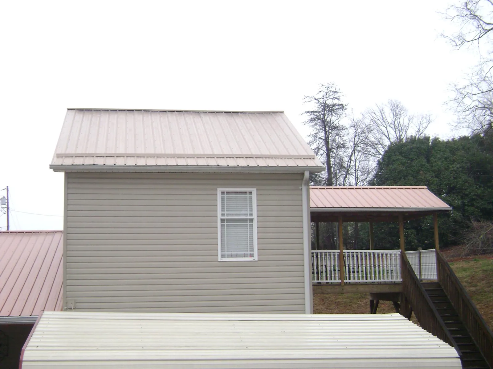 Tan metal roofs on a two story addition and attached porch, from a Roof Replacement job in Coraopolis