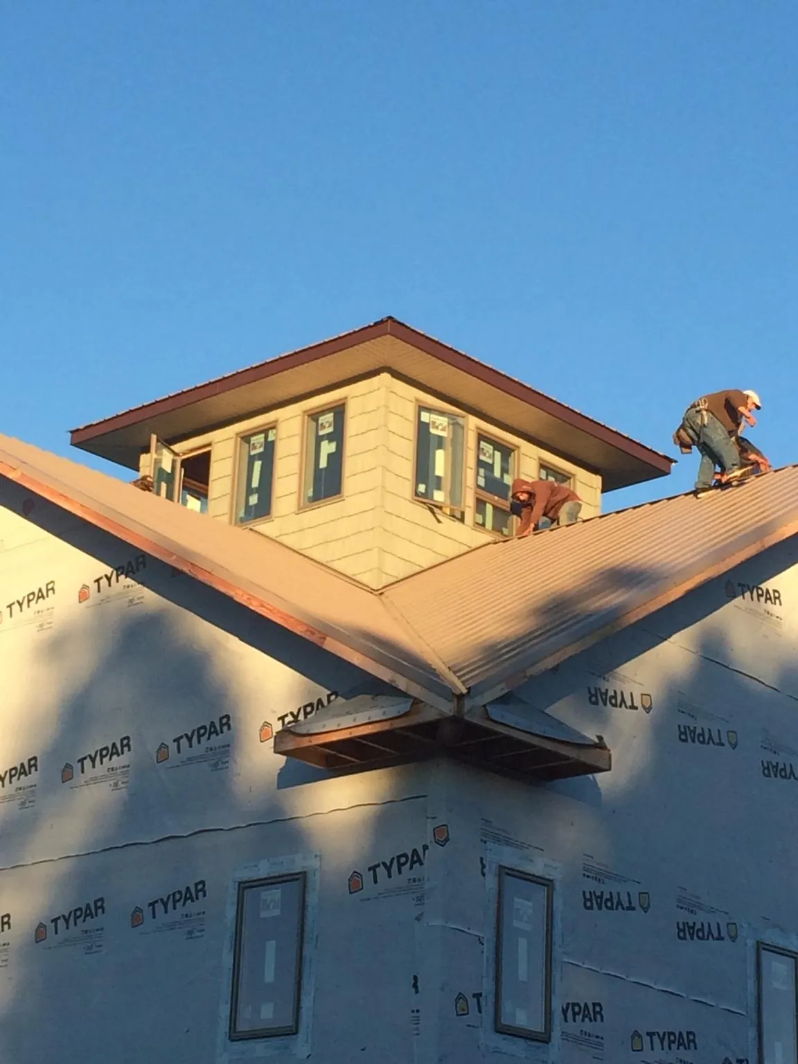 Roofers working around a rooftop cupola on a new metal roof at sunset — Roof Waterproofing in Coraopolis by Roofing Brothers